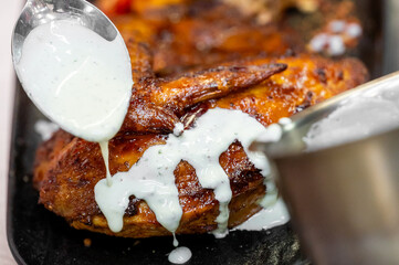 A succulent roasted chicken is drizzled with creamy sauce, adding a rich texture and flavor. The...
