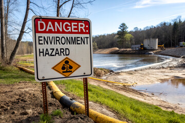 A warning sign indicating an environmental hazard near a water body, highlighting potential dangers in the area.