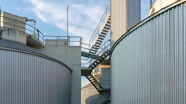 Zoon on biogas production facility closeup. Stairways to get to the top of the equipment. Blue sky.