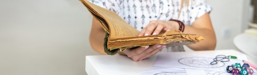 Woman fortune teller reads a book of spells. Selective focus.