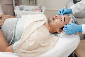 Obraz premium After laser facial treatment, A man receives cleaning cooling gel on his face. Skincare men rejuvenation concept.