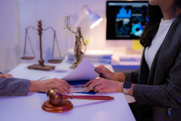 Two lawyers are exchanging money and documents in their office at night, with a gavel and scales of...