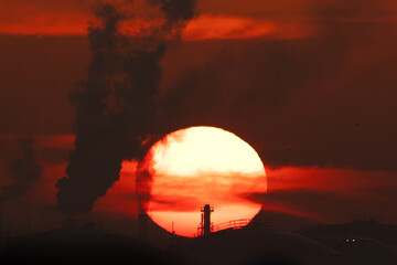 Dramatic Sunrise, chimney with smoke and oil tanks in the  morning hours at Bahrain