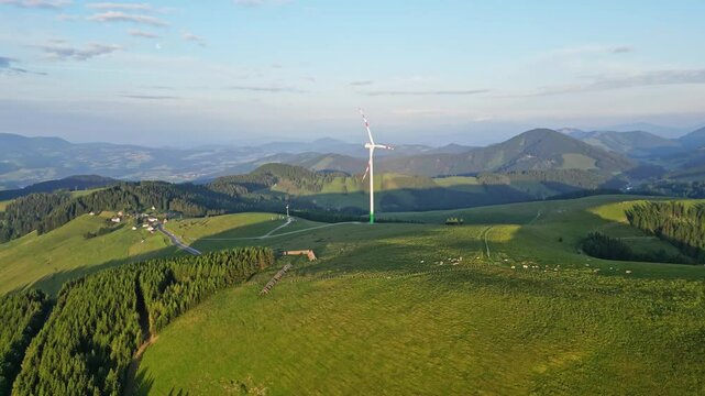 Aerial view of a beautiful alpine pasture with a windmill and scenic mountains, Sommeralm, Styria, Austria.