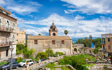 Naklejka premium Church of San Pancrazio, historic landmark in Taormina, Sicily, stands among old stone buildings with Mediterranean Sea in background