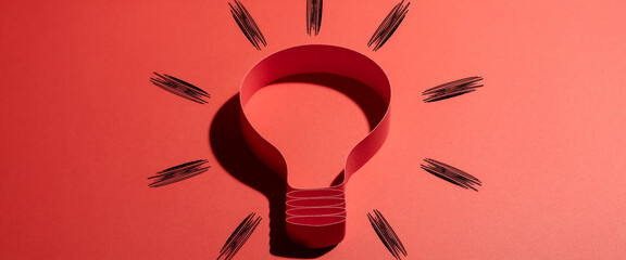 Fototapeta premium Red paper lightbulb shape on red background, surrounded by drawn rays, symbolizing idea, innovation, creativity, and inspiration, perfect for business or education concepts