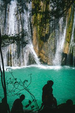 silhouettes of people walking past a waterfall at Daranak Falls, tanay, philippines.