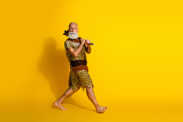 Naklejka premium Full length photo of funny funky barbarian guy dressed leopard fur holding axe walking blank space isolated yellow color background