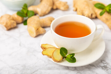 Cup of hot ginger tea with slices of ginger root on wooden background. Warming drink. Alternative medicine. Tea with honey, lemon, ginger and mint. Space for text. Copy space