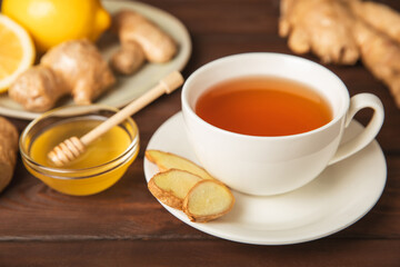 Cup of hot ginger tea with slices of ginger root on wooden background. Warming drink. Alternative medicine. Tea with honey, lemon, ginger and mint. Space for text. Copy space