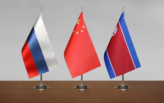 Flags China, Russia, North Korea on a gray blurred background
