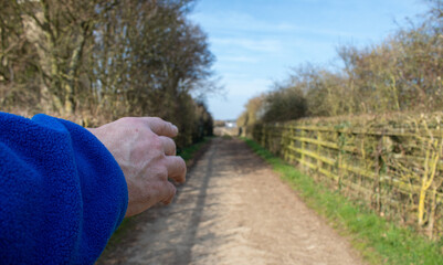 hand of a seignior showing direction on a road in the countryside