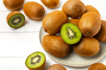 Kiwi on wooden background. Whole fruit and slices pieces of green kiwi on table. fresh ripe juicy kiwi. Tropical fruit. Organic fruit. Healthy eating. Space for text. Copy space.