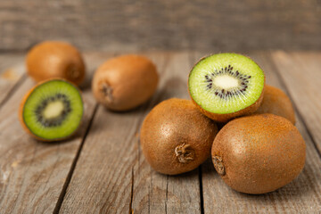 Kiwi on wooden background. Whole fruit and slices pieces of green kiwi on table. fresh ripe juicy kiwi. Tropical fruit. Organic fruit. Healthy eating. Space for text. Copy space.