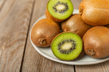 Kiwi on wooden background. Whole fruit and slices pieces of green kiwi on table. fresh ripe juicy kiwi. Tropical fruit. Organic fruit. Healthy eating. Space for text. Copy space.