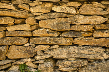 Stone wall made in a manual and rudimentary way, with stacked stones of unequal sizes. Concept background, wall, masonry, construction.
