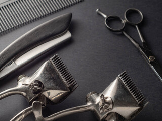 Various grooming tools including clippers, scissors, and a comb are arranged on a dark surface,...