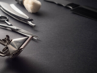 Several barbering tools, including scissors, clippers, and a comb, are neatly arranged on a dark...