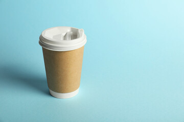 One paper cup on light blue background. Mockup for design
