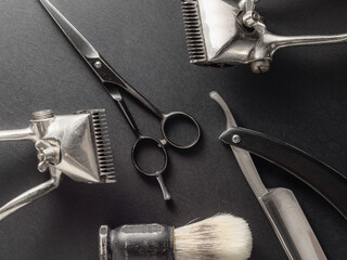 This display features traditional barber tools including clippers, scissors, and a razor on a dark surface. Each tool reflects the craftsmanship and history of grooming practices
