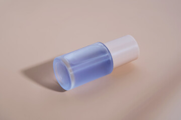 A bottle of blue serum on a delicate beige background.