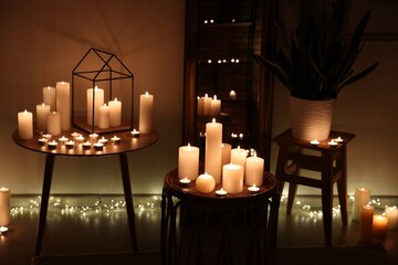 Many burning paraffin candles in dark room