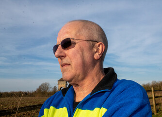 portrait of an elderly man looks into the distance wearing sunglasses
