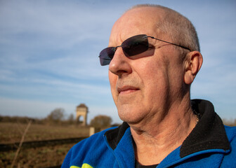 portrait of an elderly man looks into the distance wearing sunglasses