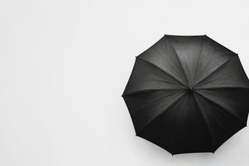 Una sombrilla negra sobre un fondo blanco, creando un contraste simple y elegante.