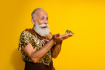Portrait of primeval caveman hold tiny dino toy empty space wear leopard skin outfit isolated on...