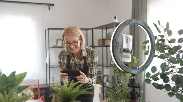 mature woman use mobile phone for live streaming and show home plants