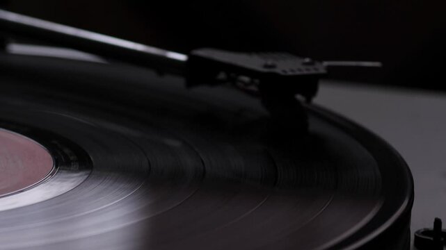 vinyl record player in which the vinyl record rotates and plays the composition close-up, the needle of the pickup on the vinyl record macro