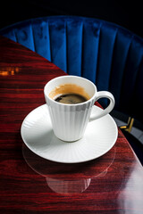 A close-up of a white porcelain cup of black coffee on the table in a restaurant