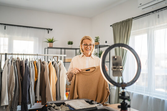 mature woman stand and show beige sweater in front camera set up