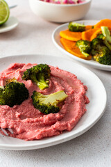 A nutritious morning meal featuring sweet potato, broccoli, radish salad with chia seeds and beet hummus for a balanced, protein-packed start