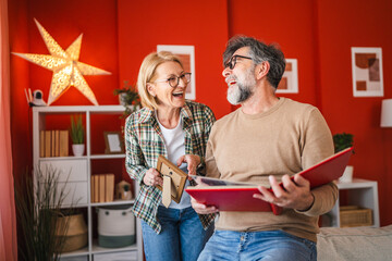 husband and wife stand and watch family photo album in the living room