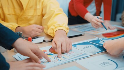 A dynamic team engages in a collaborative brainstorming session at a modern workspace, examining colorful charts and discussing business strategies. SACTR