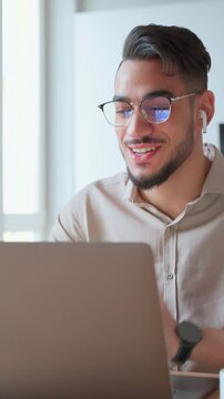 Young adult Indian businessman having business videocall with college at online conference meeting. Mature arabian smiling man studying learning course using pc laptop webcam at home office. Vertical