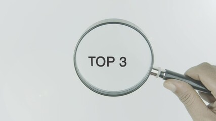 Top 3 text or word highlighted by a magnifying glass in a hand on a white background, symbolizing priority, ranking, and the highest tier in a selection or list