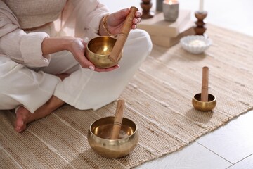 Woman with singing bowls on floor indoors, closeup