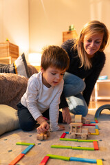 Child playing with wooden toys while mother watches: building a road with colorful blocks