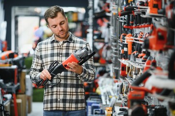 A male buyer chooses power tools in a hardware store. A large selection of tools