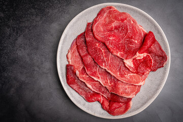 Raw organic steak with ingredients for cooking on a gray background. Top view with copy space. High quality photo