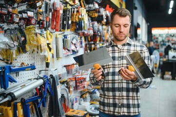 A man in a hardware store choosing a tool