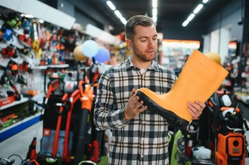 Man chooses rubber boots at a garden supply store