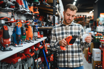 man choosing electric shears in gardening tools store