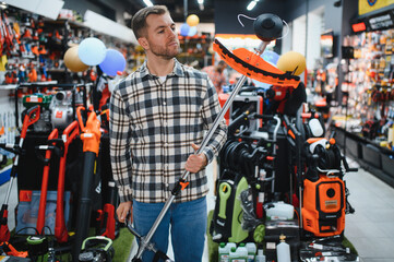 A man in a hardware store choosing a tool