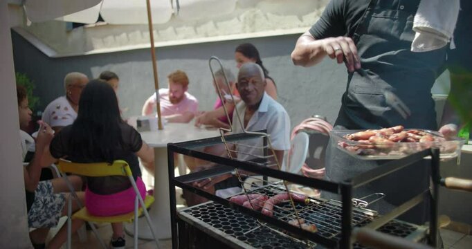 Friends and family enjoying a barbecue gathering with grilled food, showcasing a multicultural community bonding over shared meals in a relaxed outdoor setting