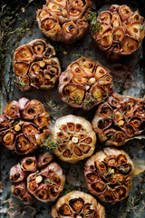 Close-up view of roasted garlic bulbs with thyme. Garlic background