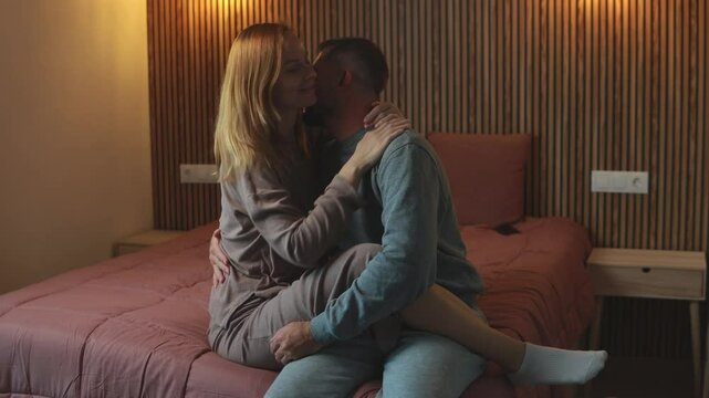 Romantic couple enjoy tender moments, embracing and kiss on  comfortable bed in softly lit bedroom, creating warm and intimate atmosphere